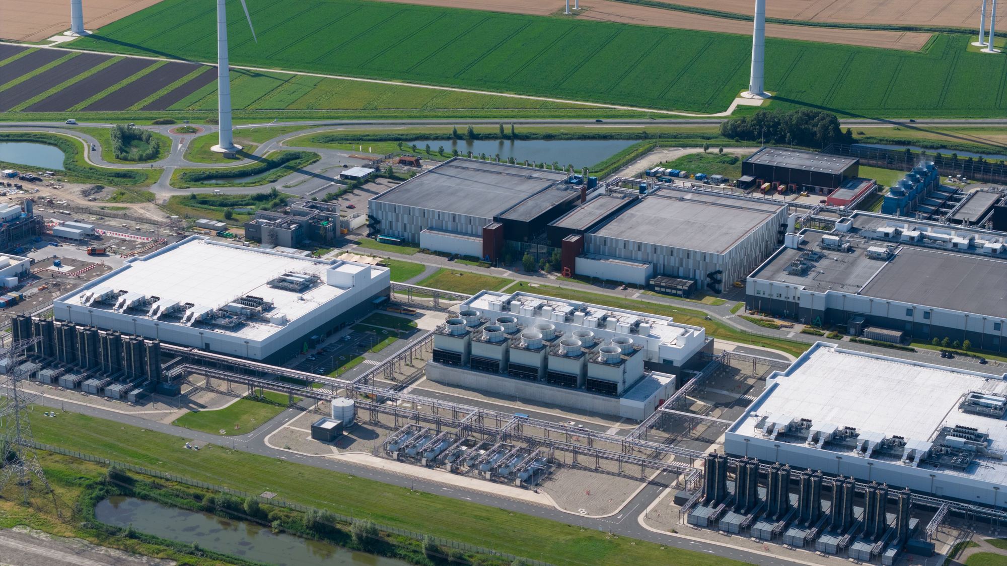 Aerial view of a large computing campus surrounded by farmland and wind turbines