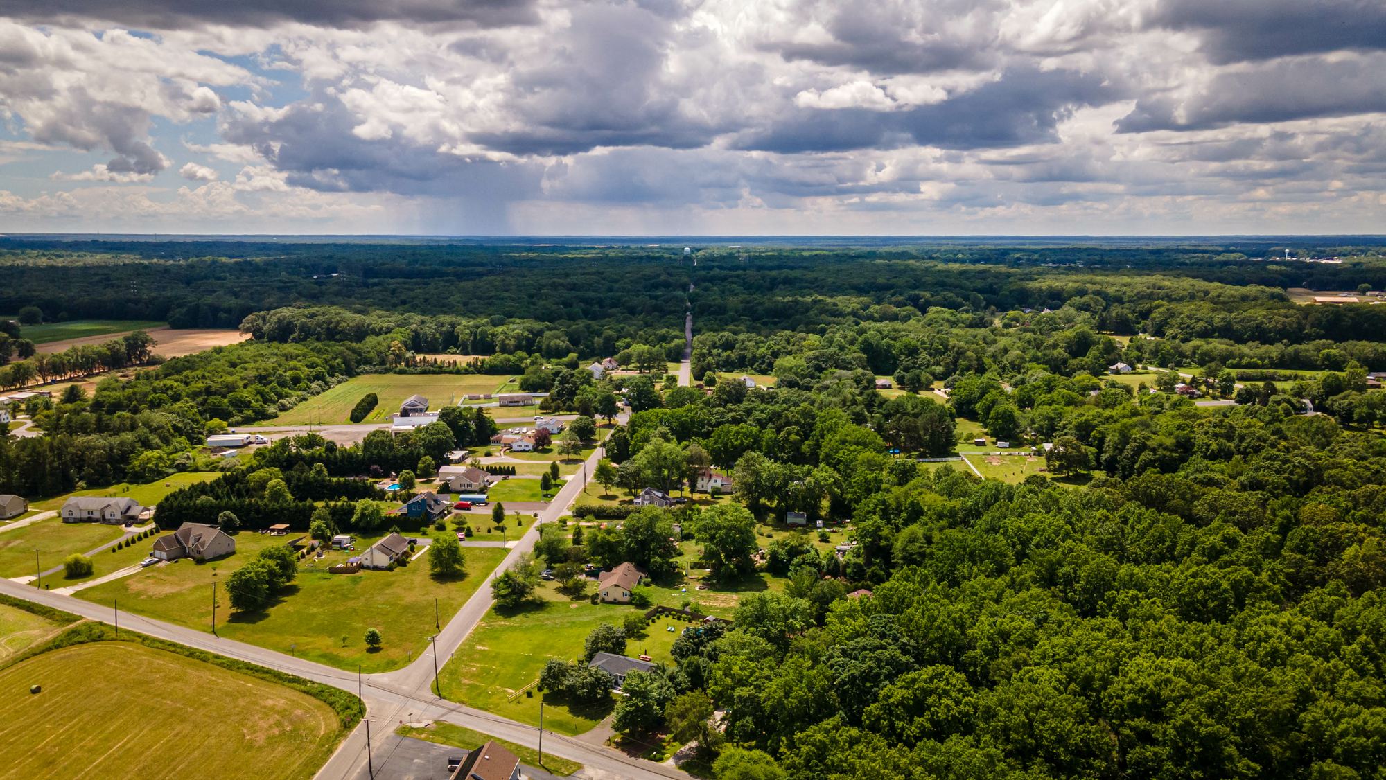Aerial view of a rural community of homes, fields and tree cover